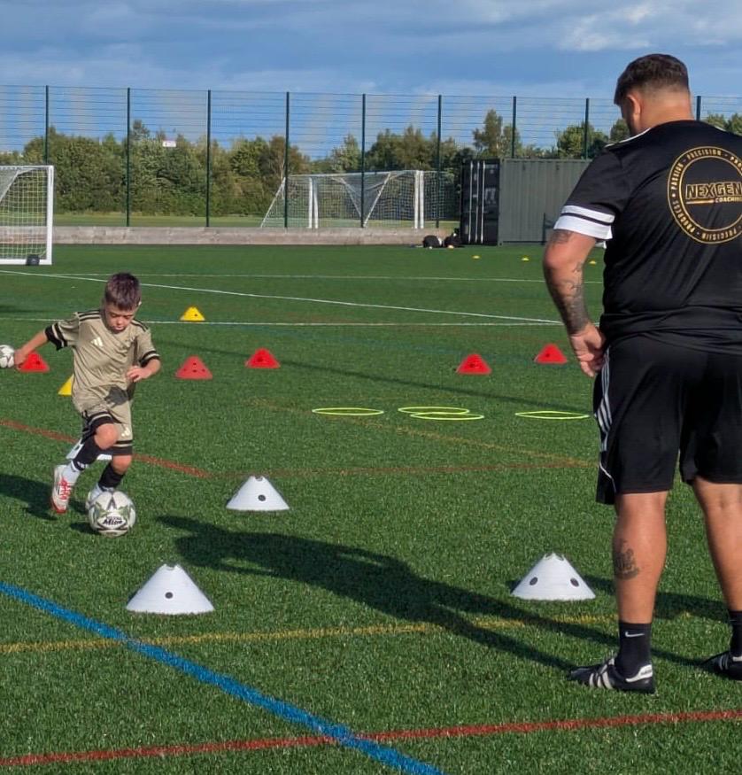 Nexgen coach watching closely as a young player dribbles through cones