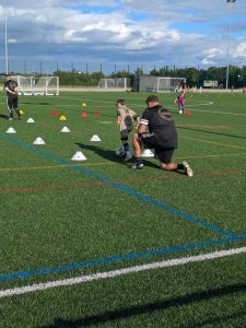 A Nexgen coach setting out cones and working with young players on a 3G pitch