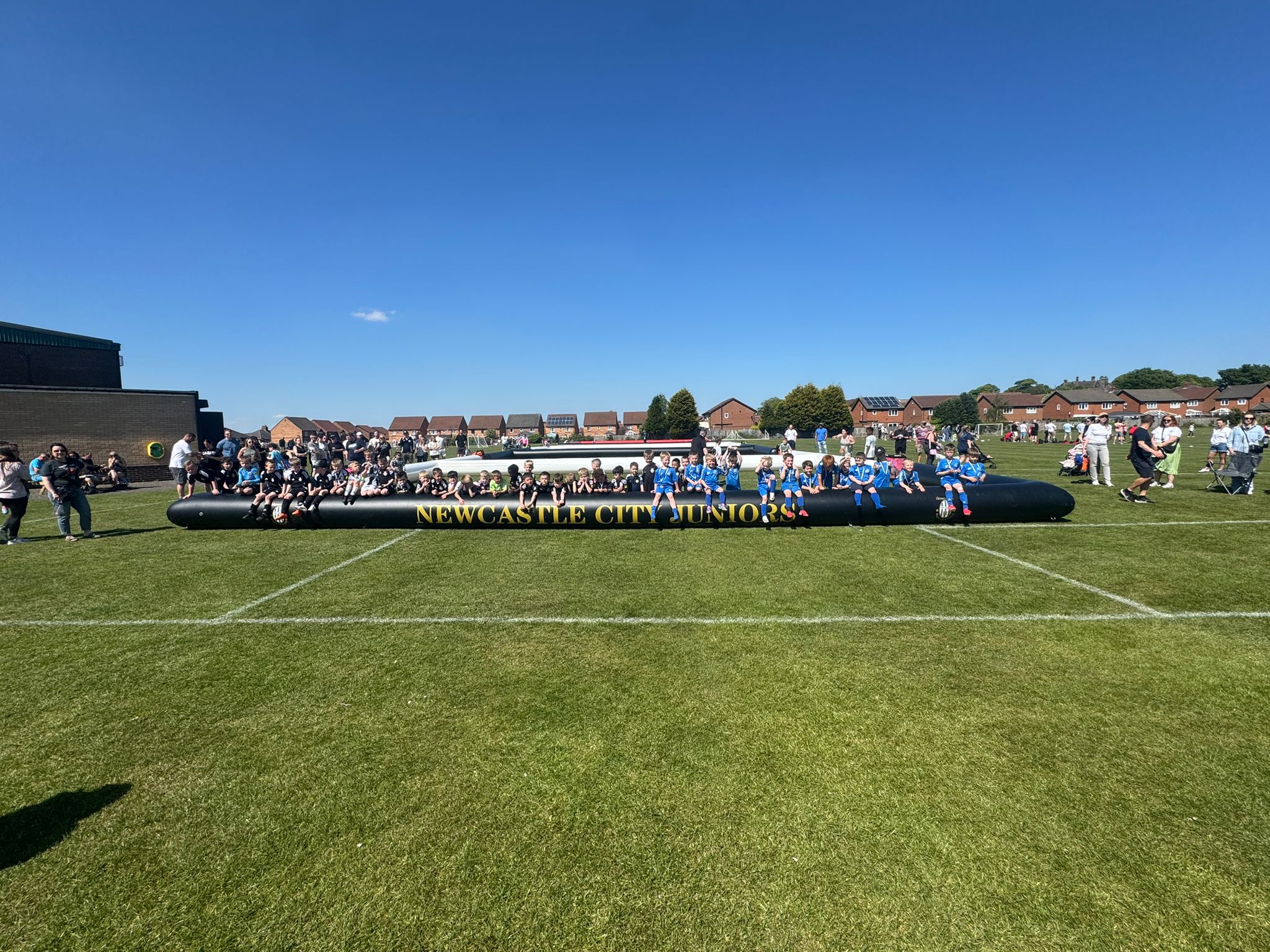 Wide view of a busy outdoor football event on a sunny day